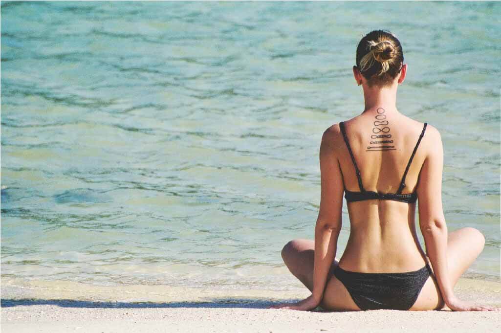 iyengar yoga girl sitting up straight in perfect alignment on the beach facing the ocean