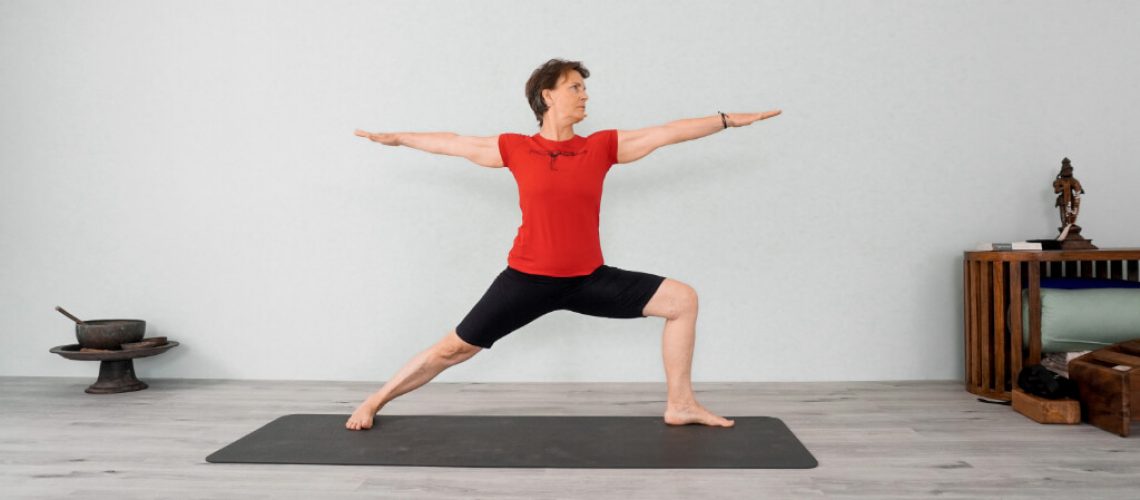 Senior Iyengar Yoga Teacher Kathy Cook doing warrior pose 2