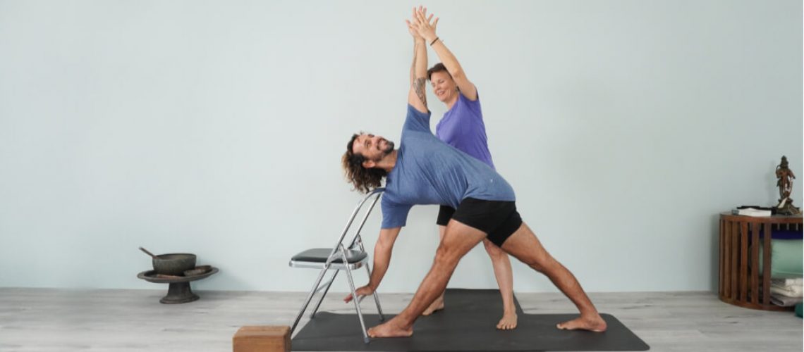 Senior Iyengar Yoga Teacher Kathy Cook and Juan Carlos demonstrate a triangle pose with chair