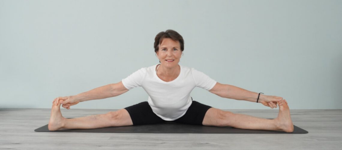 Senior Iyengar Yoga Teacher Kathy Cook demonstrate a Wide Angle Forward Bend pose